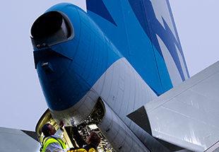  Picture of a man in safety gear inspecting tail of commercial plane. Maintenance & Engineering